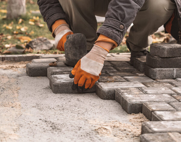 Laying paving slabs close-up. Road surface, construction. Sidewalk repair. Worker laying stone paving slab. Laying tiles in the city park garden .